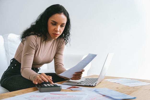 Una giovane donna stressata ha problemi finanziari con il debito della carta di credito per pagare il concetto cruciale di cattivo denaro personale e crisi di gestione della retribuzione del mutuo triste e infelice