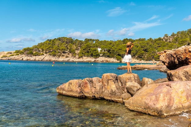 Una giovane donna sugli scogli in vacanza a Ibiza sulla spiaggia di Salada y Saladeta Baleari