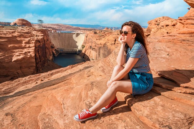 Una giovane donna sulle rocce rosse ammira la vista della diga del Glen Canyon Arizona