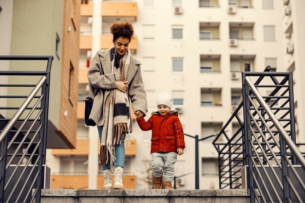 Una giovane donna tata che si tiene per mano con un ragazzino e va a fare una passeggiata Concetto di babysitter