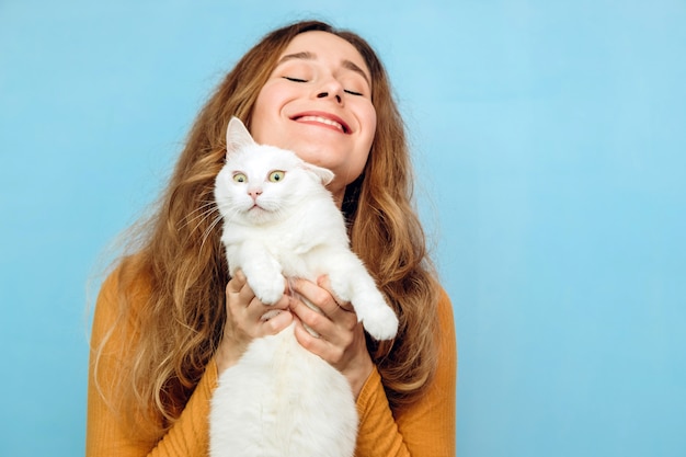 Una giovane donna tiene in braccio un gatto bianco.