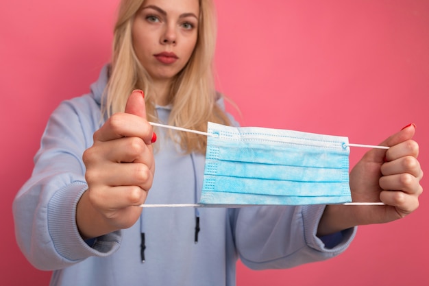 Una giovane donna tiene in mano una maschera protettiva blu