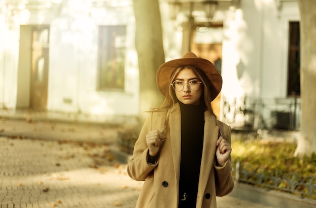 Una giovane donna vestita con un cappotto, un cappello e con uno zaino sta camminando nella città europea d'autunno