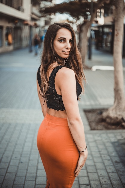 Una giovane donna vestita con una gonna rossa e un top, cammina per le strade della città. Concetto femminile.