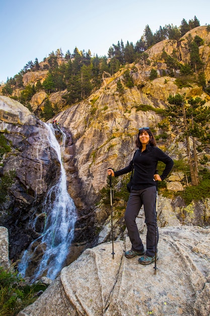 Una giovane donna vicino a una gigantesca cascata di Banos de Panticosa