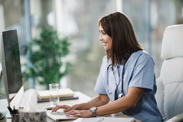 Una giovane dottoressa attraente che utilizza un computer mentre era seduta nella sua stanza di consulenza.