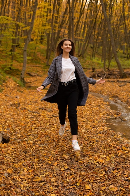 una giovane e bella ragazza corre attraverso la foresta autunnale della città