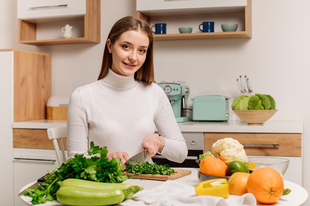 Una giovane e bella ragazza vegetariana o blogger prepara la colazione a base di frutta, verdura e verdura a casa in cucina Blog sul mangiare sano