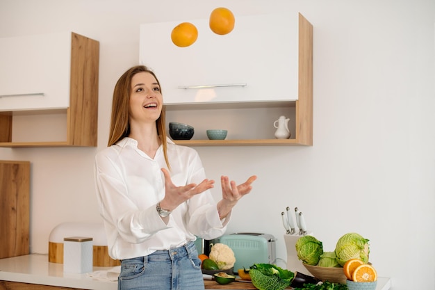 Una giovane e bella ragazza vegetariana o blogger prepara la colazione a base di frutta, verdura e verdura a casa in cucina Blog sul mangiare sano