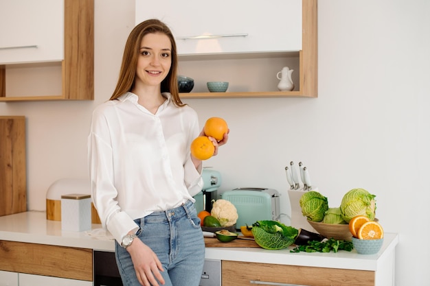 Una giovane e bella ragazza vegetariana o blogger prepara la colazione a base di frutta, verdura e verdura a casa in cucina Blog sul mangiare sano