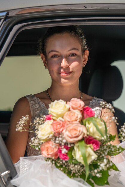 Una giovane e bella sposa in macchina tiene tra le mani un bouquet da sposa