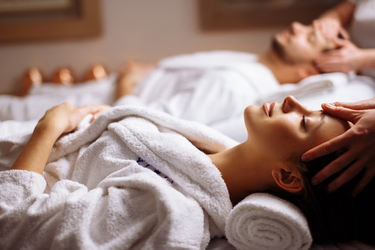 Foto una giovane e bellissima coppia felice che si gode un massaggio alla testa alla spa.