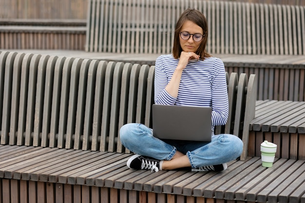 Una giovane e sicura blogger o donna di marketing che beve caffè e lavora al suo laptop lavora in a