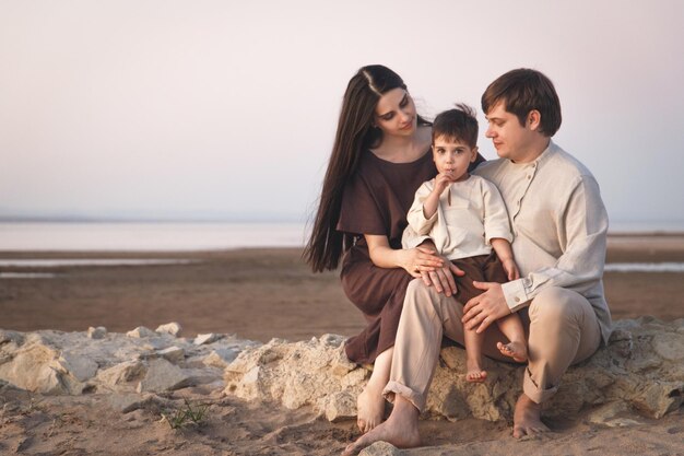 Una giovane famiglia di 3 persone trascorre del tempo insieme sulla spiaggia Abiti di lino dall'aspetto familiare Copia spazio