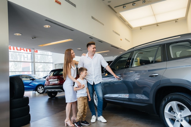 Una giovane famiglia felice sceglie e acquista una nuova auto presso un concessionario di automobili. L'acquisto di una nuova auto.