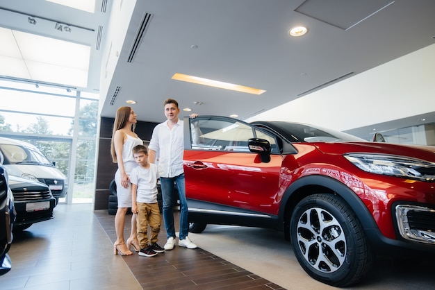 Una giovane famiglia felice sceglie e acquista una nuova auto presso un concessionario di automobili