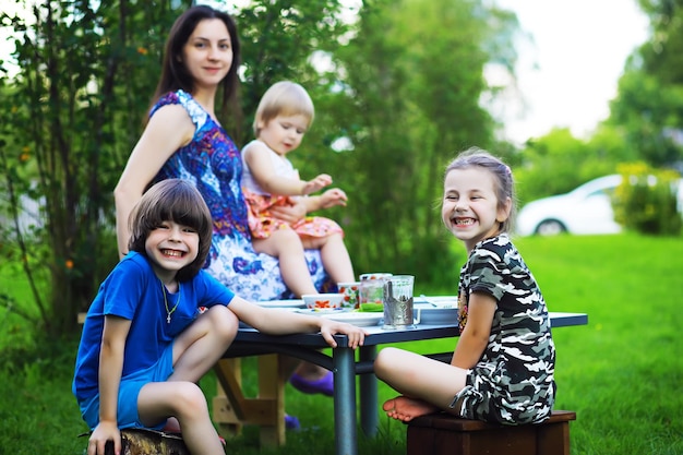 Una giovane famiglia numerosa a un picnic in una mattina d'estate. Una bella madre con bambini sta facendo colazione nel parco.