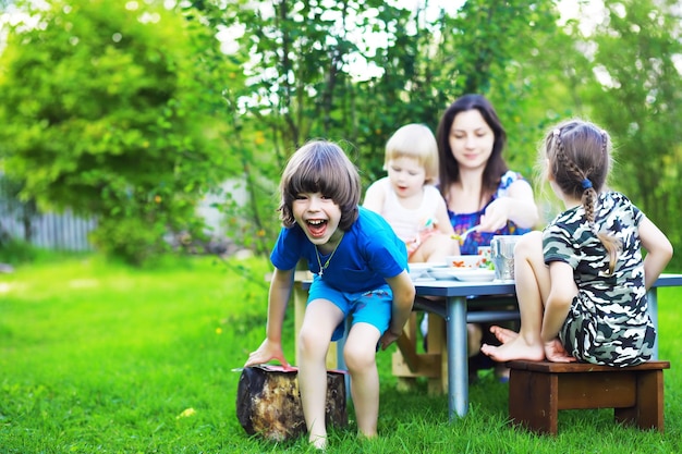 Una giovane famiglia numerosa durante un picnic in una mattina d'estate. Mamma con bambini sta facendo colazione nel parco