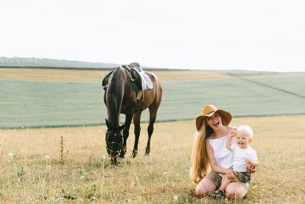 Una giovane famiglia si diverte sul campo. Genitori e figlio con un cavallo