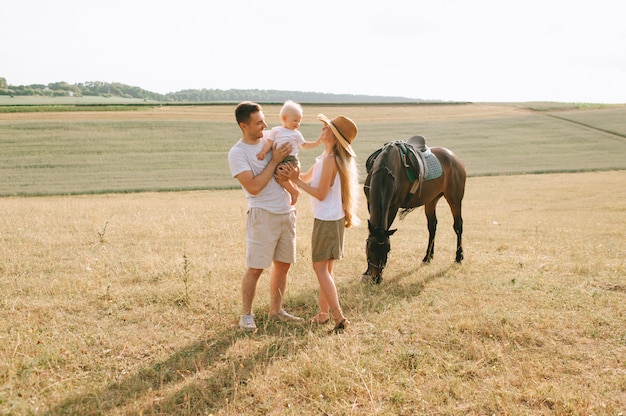 Una giovane famiglia si diverte sul campo. Genitori e figlio con un cavallo