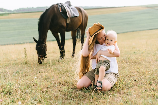 Una giovane famiglia si diverte sul campo. Genitori e figlio con un cavallo