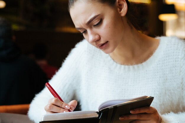 Una giovane freelance si siede in un bar, scrive su un taccuino, si concentra