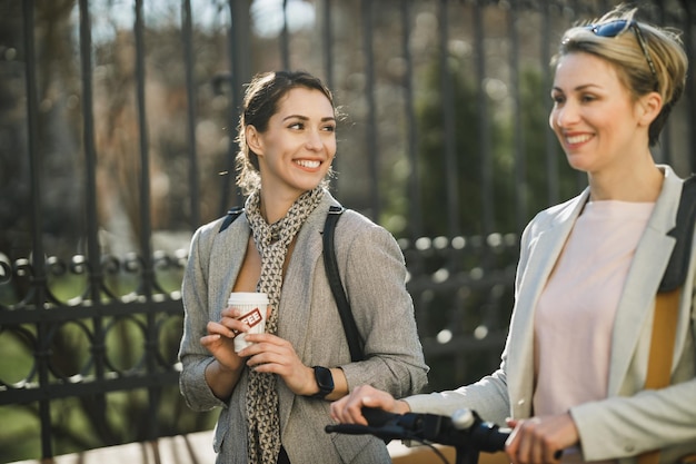 Una giovane imprenditrice di successo che fa una pausa caffè e chiacchiera mentre cammina con il suo collega.