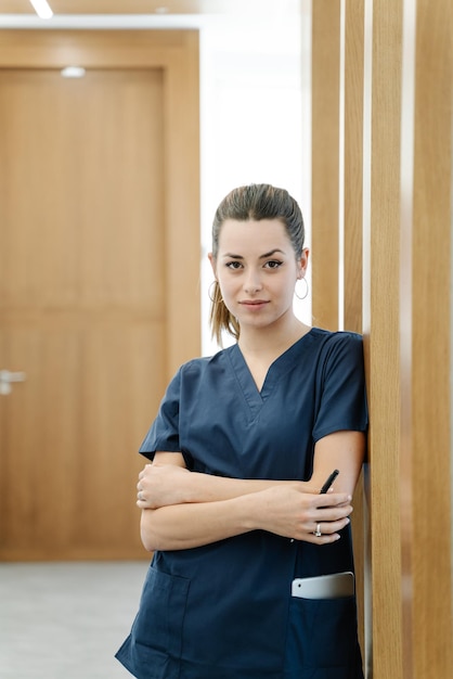 Una giovane infermiera con una giacca blu sorride nel corridoio di una clinica odontoiatrica davanti alla telecamera