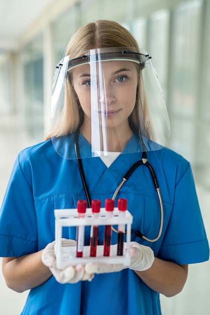 Una giovane infermiera in uniforme porta in laboratorio provette con campioni di sangue. Concetto di medicina