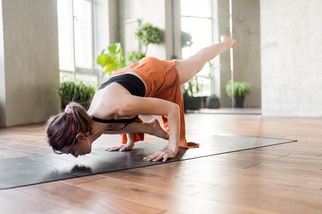 Una giovane istruttrice di yoga si allena su una stuoia in un moderno fitness club interno