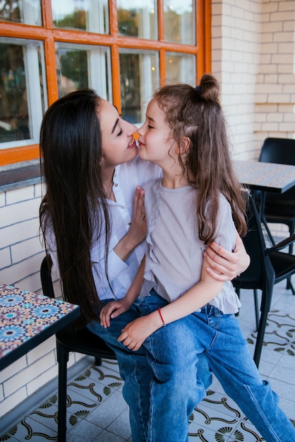 una giovane madre abbraccia la sua piccola figlia. la ragazza è seduta tra le braccia di una donna.