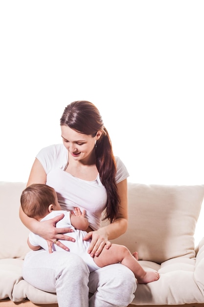 Una giovane madre allatta un bambino piccolo. Stanno giocando sul divano