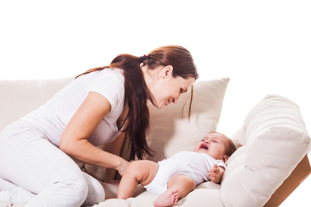 Una giovane madre calma un bambino piccolo. stanno giocando sul divano