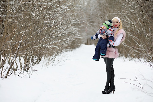 Una giovane madre cammina in una giornata invernale con un bambino in braccio nel parco