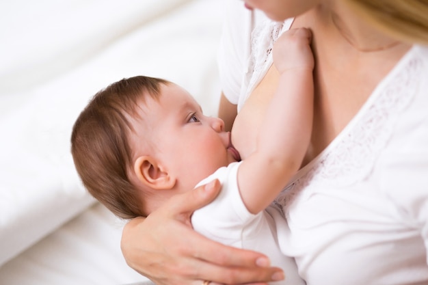 Una giovane madre che allatta al seno la sua piccola bambina tenendola tra le braccia