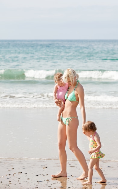 Una giovane madre che cammina in spiaggia con i suoi figli