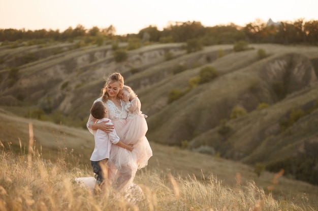 Una giovane madre con bambini cammina in un campo al tramonto