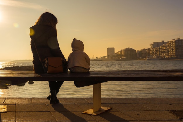 Una giovane madre con il suo bambino al tramonto su Playa del Cura nella città costiera di Torrevieja