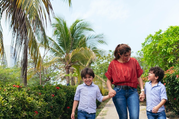 Una giovane madre e i suoi bambini piccoli che camminano nel parco.