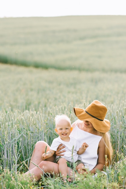 Una giovane madre e il suo bambino seduti vicino al grano