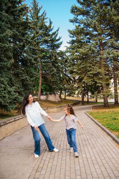 Una giovane madre e la sua piccola figlia stanno ballando nel parco. Una ragazza e una donna stanno volteggiando sul marciapiede.