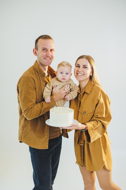 Una giovane madre e un giovane padre felici che tengono il loro figlio appena nato tra le braccia e gli danno una torta I genitori che festeggiano il loro compleanno con il loro bambino Il concetto di vacanze in famiglia