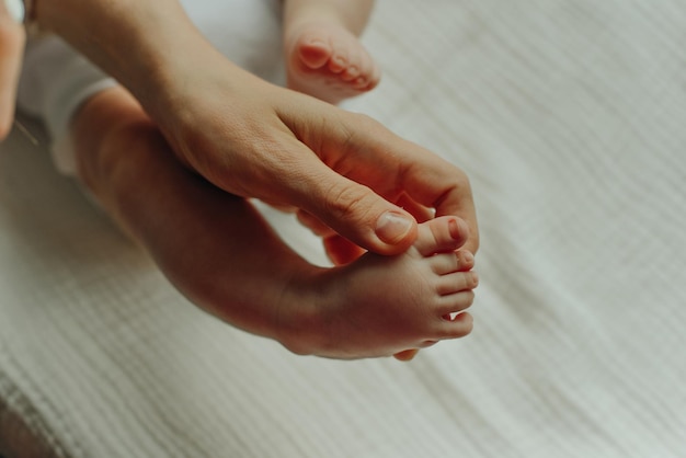 Una giovane madre e un neonato gambe di un bambino nei palmi di una famiglia di amore dei genitori di una donna