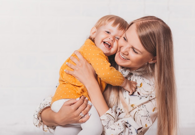 Una giovane madre felice abbraccia la sua bambina su uno sfondo luminoso. Comunicazione madre-figlio