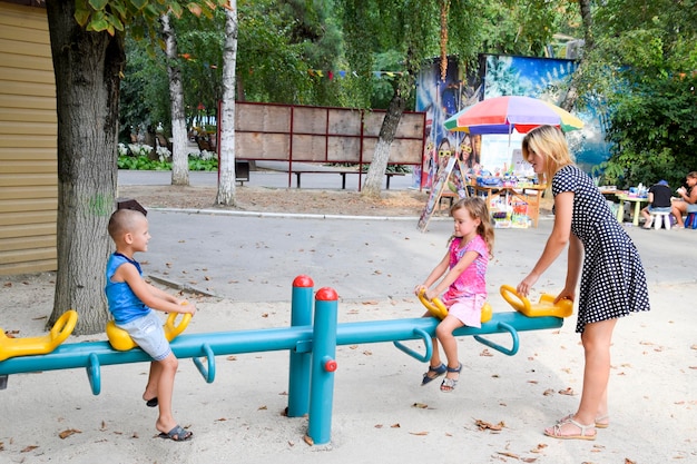 Una giovane madre gioca con i bambini nel parco giochi