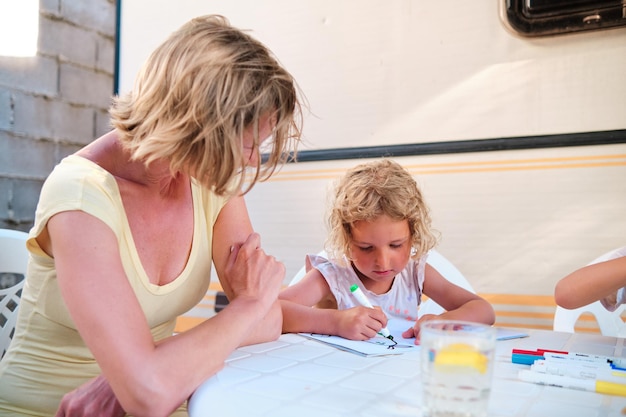 Una giovane madre in vacanza insegna a sua figlia a disegnare nella sua roulotte