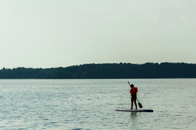 Una giovane madre nuota su una tavola da paddle in piedi Tavola SUP Sport acquatici