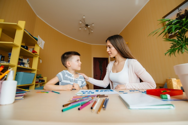 Una giovane madre sta facendo i compiti con la madre a casa. Genitori e formazione.