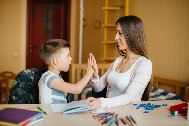 Una giovane madre sta facendo i compiti con suo figlio a casa. Genitori e formazione