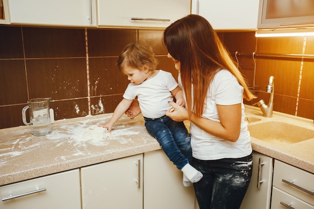 una giovane madre sta in cucina e lavora con la farina insieme al figlio